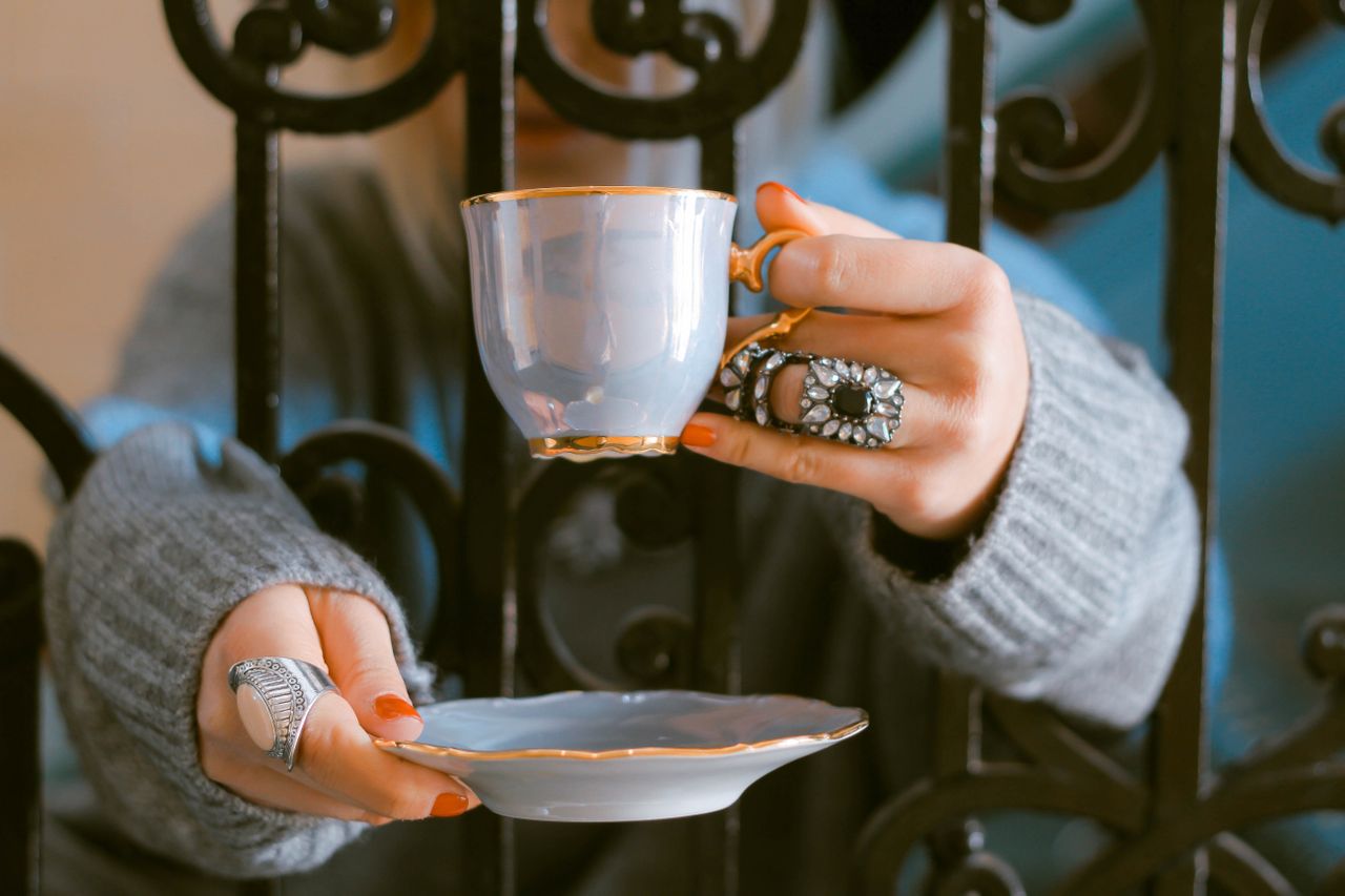 Woman wearing an onyx and opal fashion ring, plus a white enamel ring on the other hand