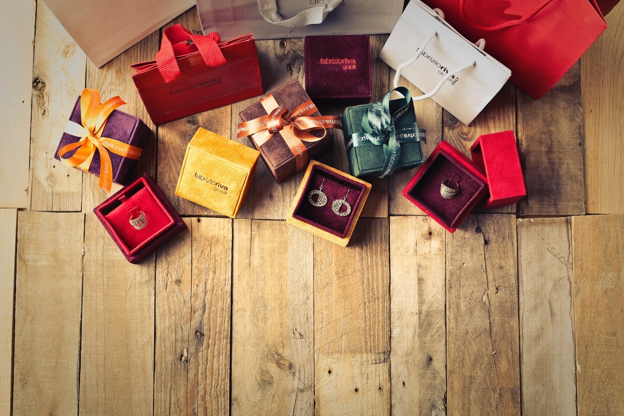 A group of designer jewelry gifts sit scattered on a wooden living room floor