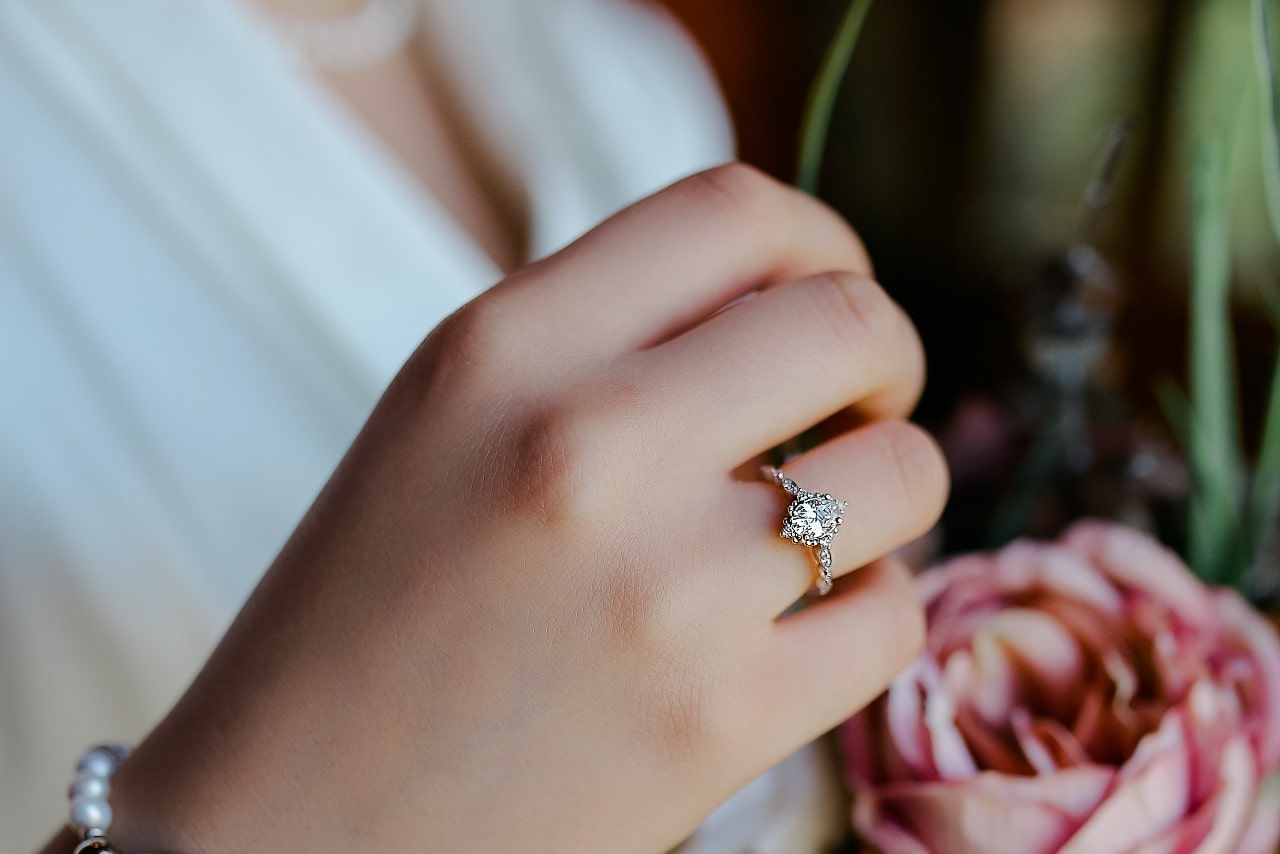 A woman wearing white sports a marquise diamond engagement ring