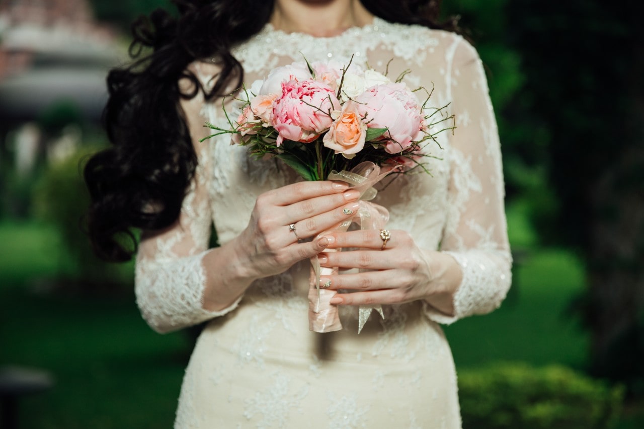 A woman wearing a wedding dress holds a bouquet