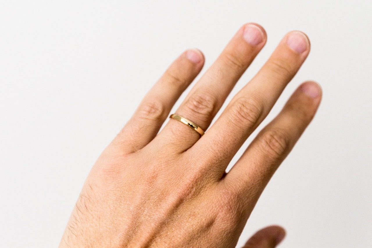 Hand showing off a polished yellow gold band.