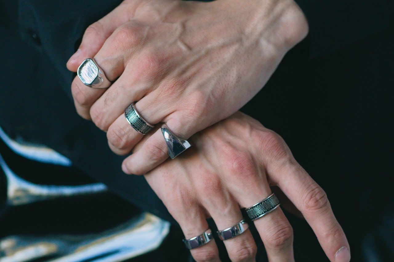 a pair of hands wearing seven silver fashion rings