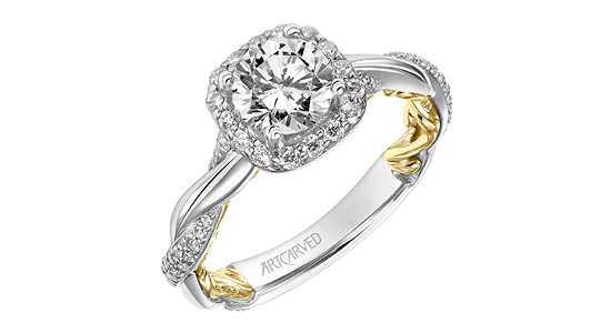 A mixed metal engagement ring with intertwining bands and side stones and a halo setting