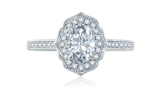 A platinum oval cut engagement ring with milgrain detailing, a halo, and sidestones
