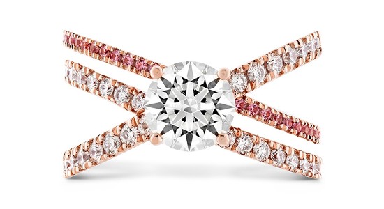 A three band, rose gold engagement ring featuring a round cut center stone and diamond and pink sapphire side stones