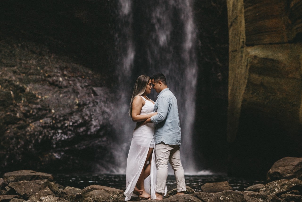 A couple embraces at a waterfall