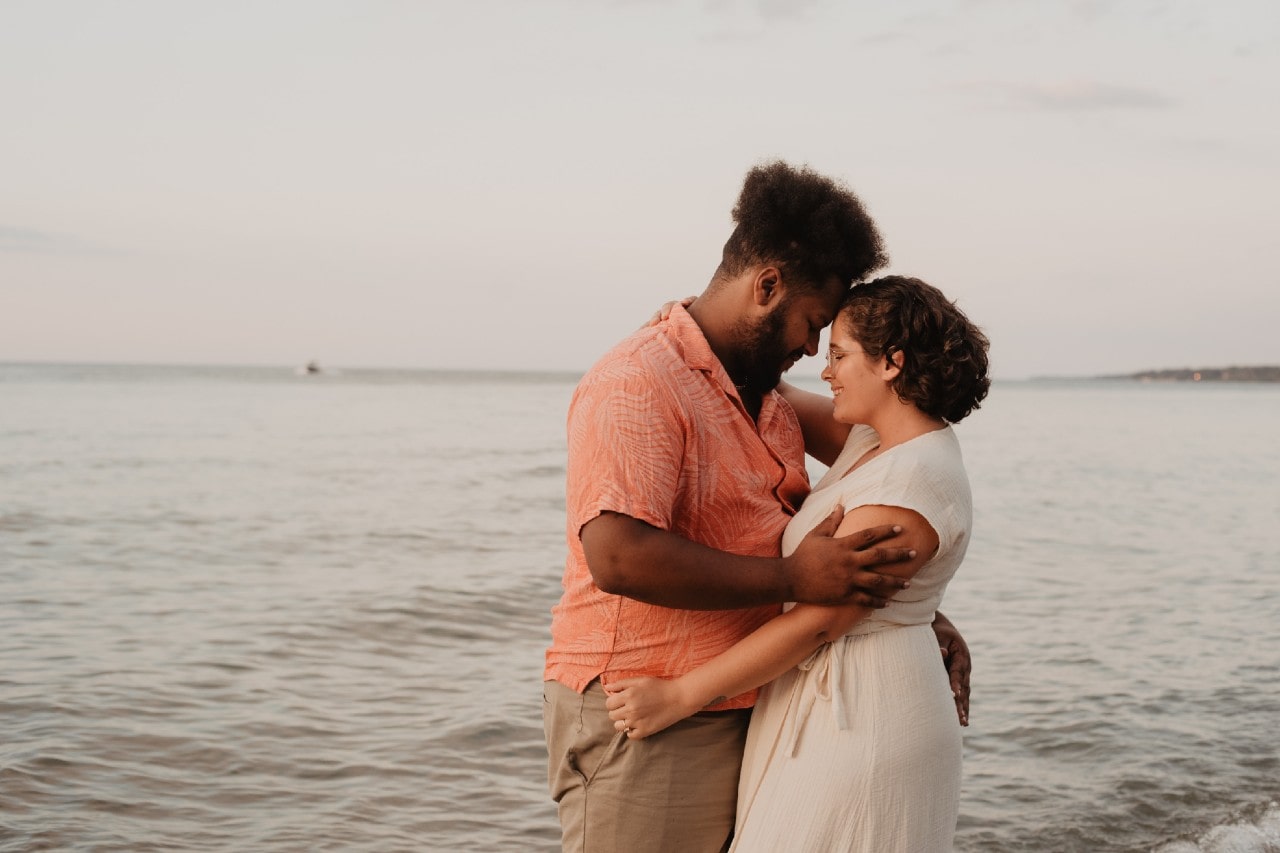 A couple embraces at the beach while the sunsets