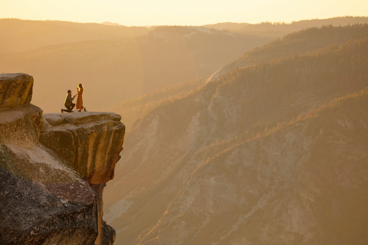 A man proposing to a woman on a high cliff in Yosemite National Park.