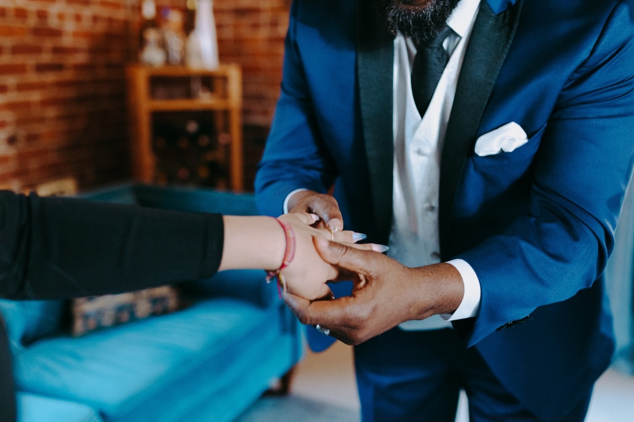 A man looks at the engagement ring on his beloved’s hand.