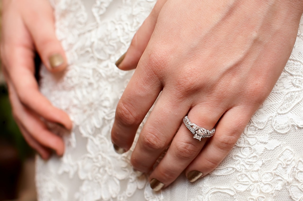 close up of a bride’s diamond engagement ring and wedding band