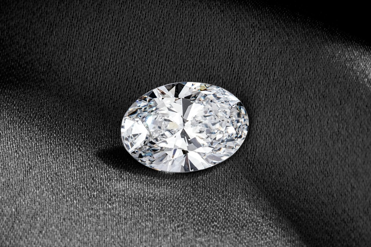 an oval cut diamond lying on a gray piece of fabric