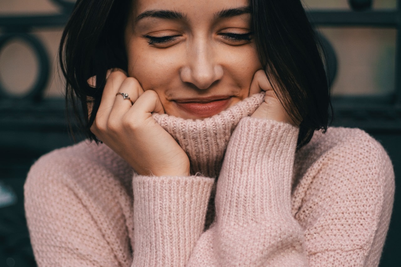 A close-up of a young woman in a cozy turtleneck sweater.