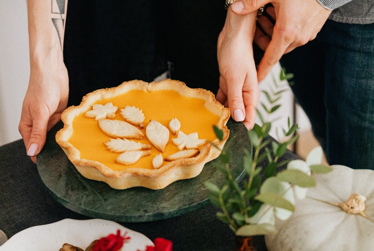 A close-up of a couple preparing a pumpkin pie on Thanksgiving.