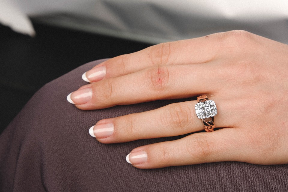 A close-up of a woman’s well-manicured hand wearing an opulent and distinctive engagement ring.