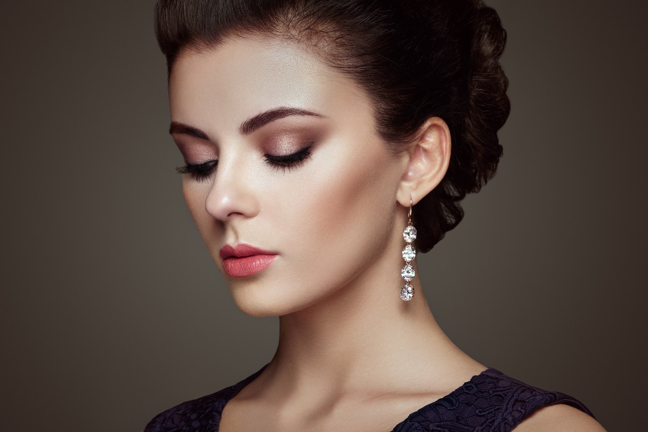 A woman in a formal dress wears a pair of diamond drop earrings.