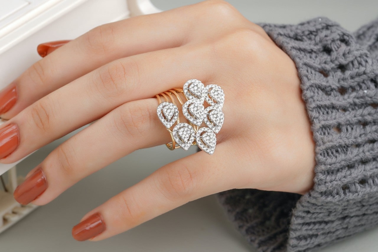 A closeup of a two-tone diamond ring on a woman’s manicured hand.