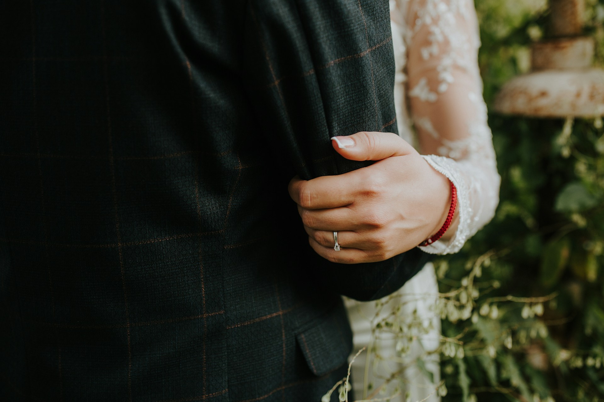 A close-up of a newlywed couple dancing, a wedding ring visible on the bride’s hand.