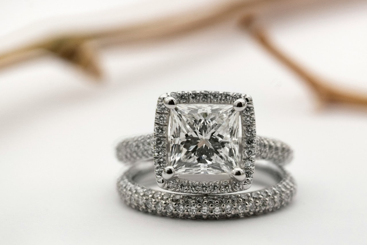 A close-up of a stunning engagement ring and wedding band set, both encrusted with shimmering diamonds.