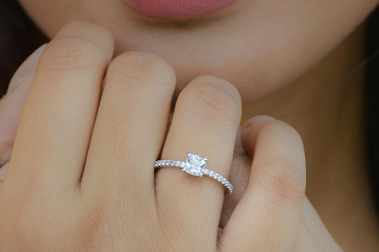 close up of a woman’s hand wearing an asscher cut engagement ring