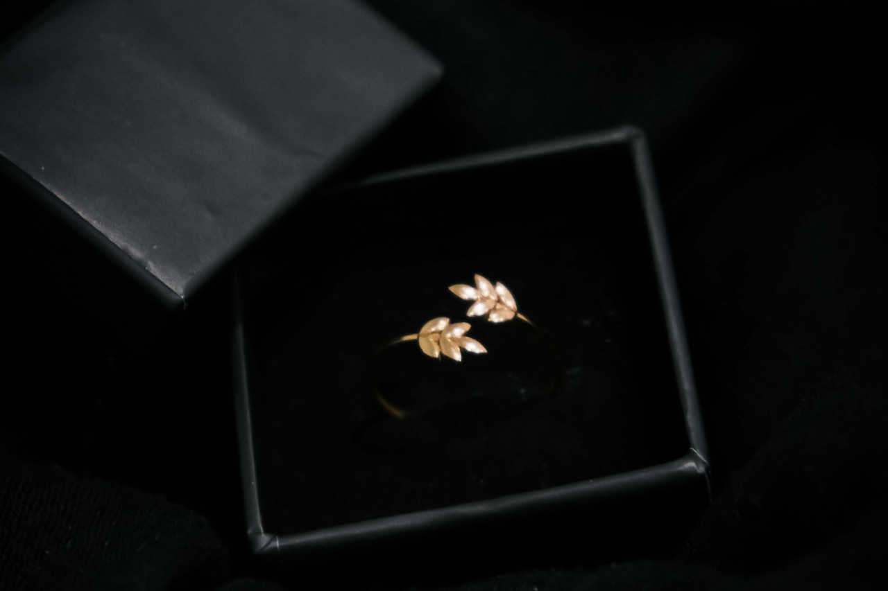 a yellow gold ring with leaf motifs in a black ring box