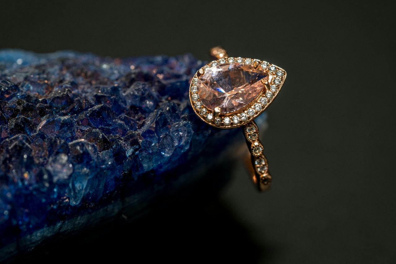 A unique pear-cut engagement ring displayed on the edge of a stunning blue stone.