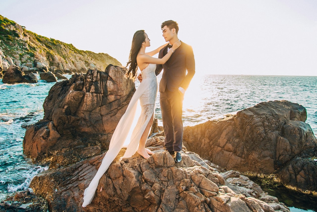 couple standing on rocks near beach