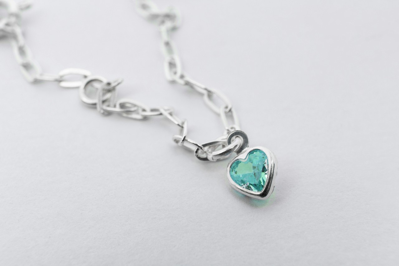 A close-up of a simple yet elegant necklace with a heart shaped topaz pendant.